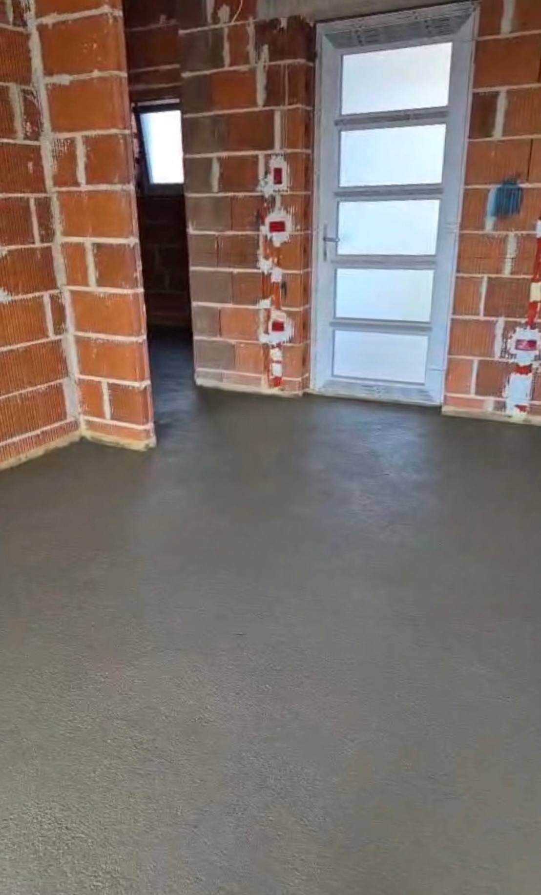 Prostorija u gruboj fazi s neožbukanim zidovima od blok opeke i gotovom sivom glazurom do zidova